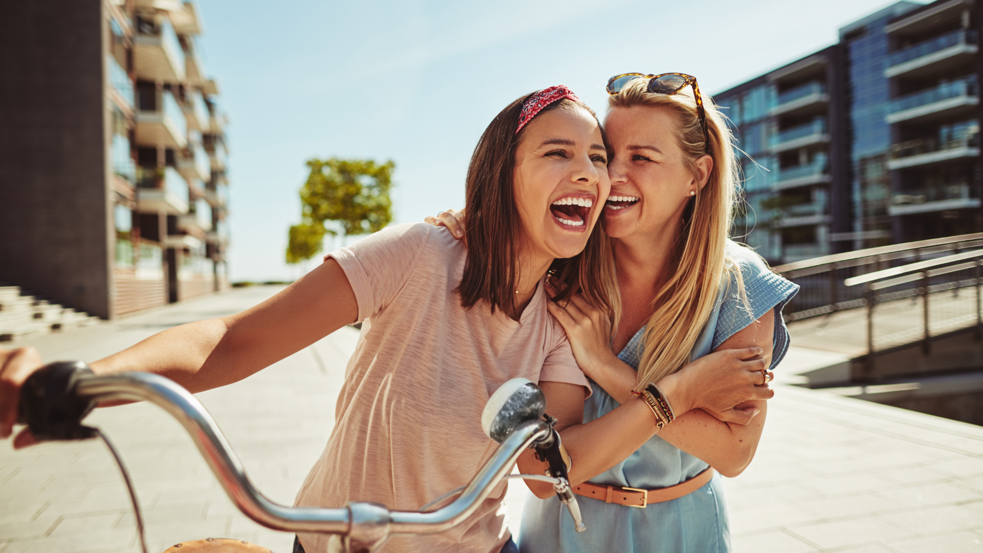 Two girls smiling while riding a bike